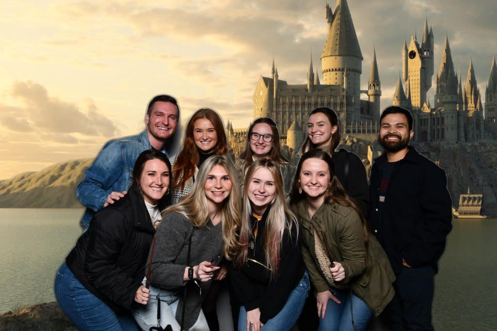 Group of friends stand in front of green screen showing Hogwarts at Harry Potter: The Exhibition